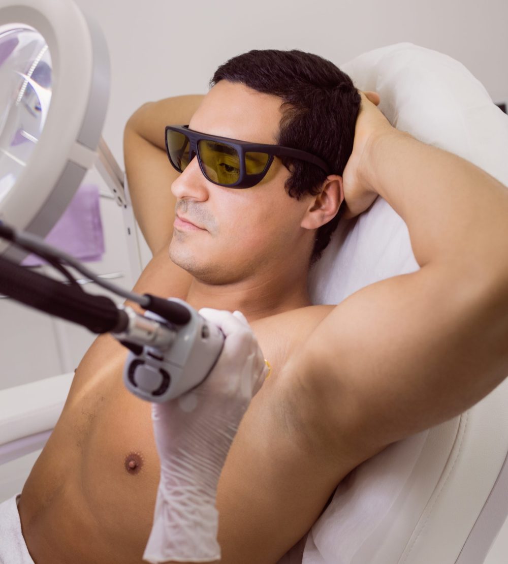 Doctor performing laser hair removal on male patient skin in clinic